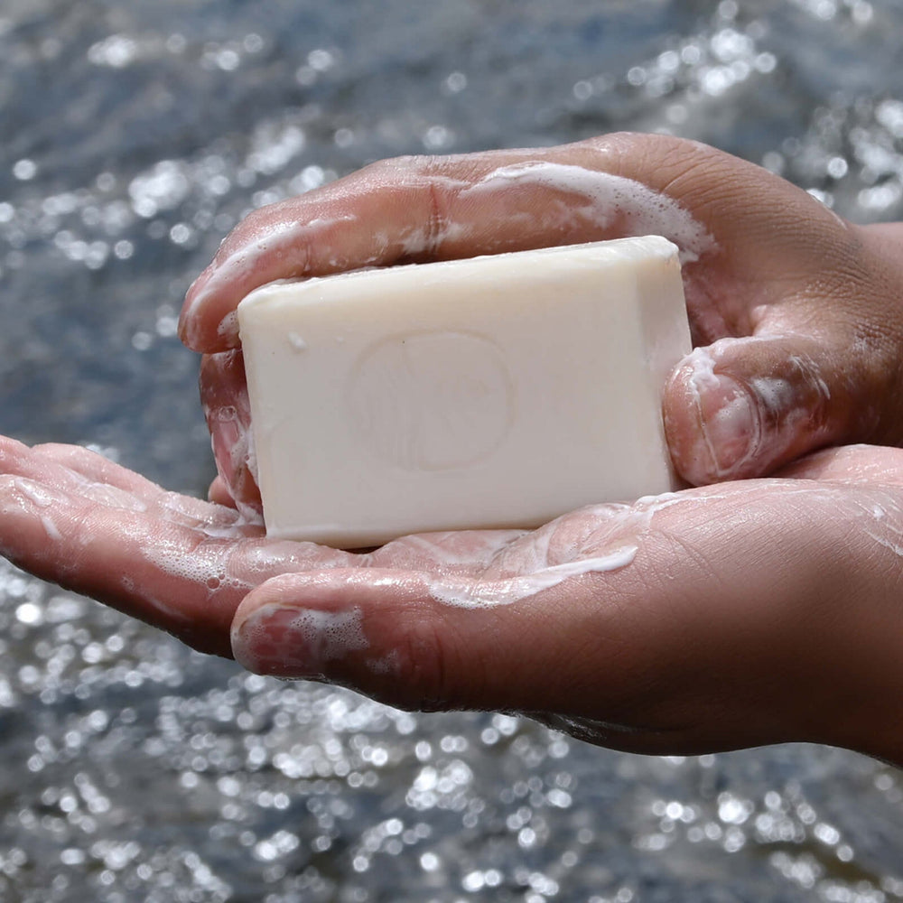 
                      
                        Tsoji handmade all natural soap in hands with rich lather with the mountain lake as the background
                      
                    